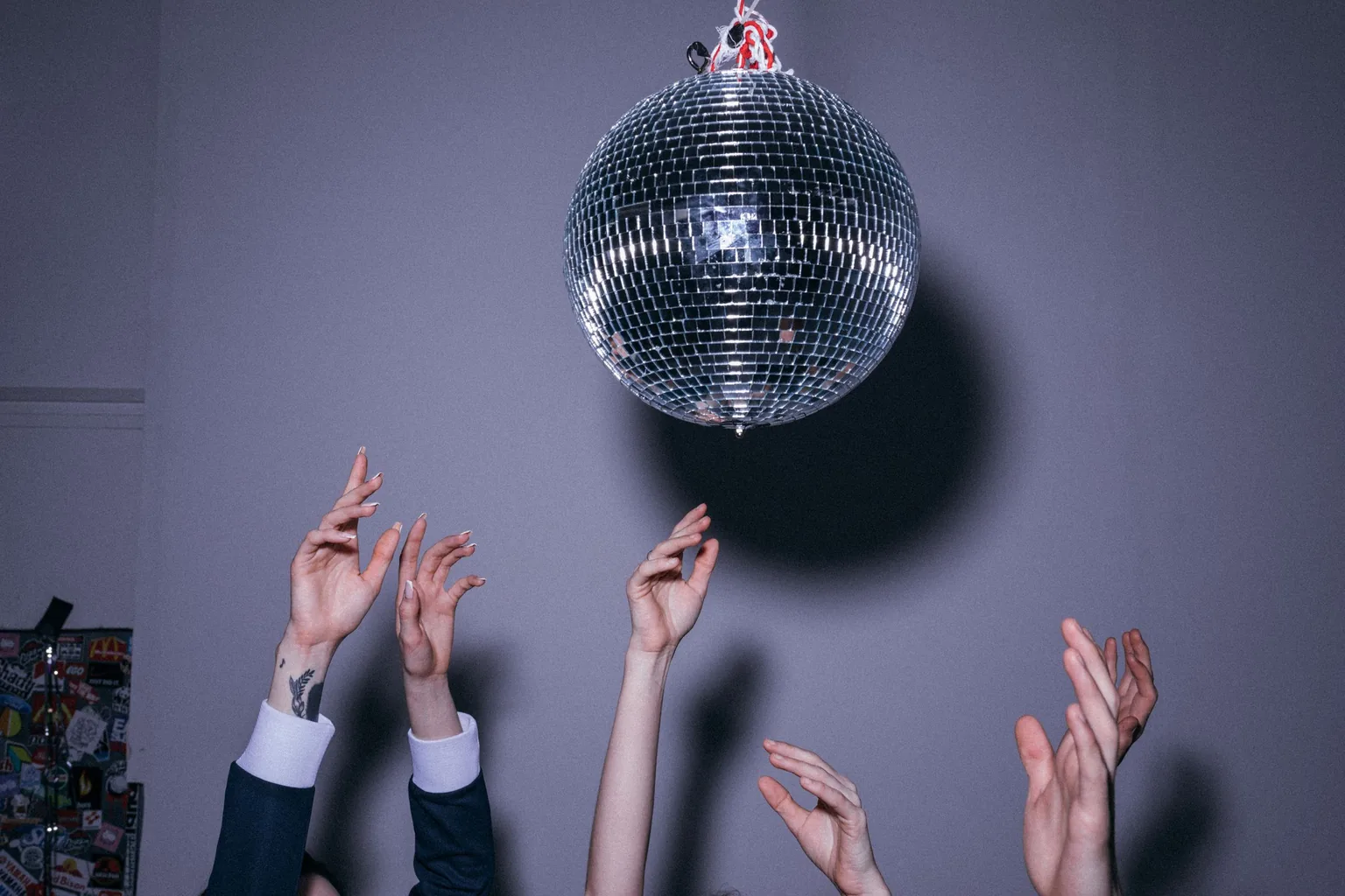 Hænder strækker sig mod en discokugle sent på aftenen