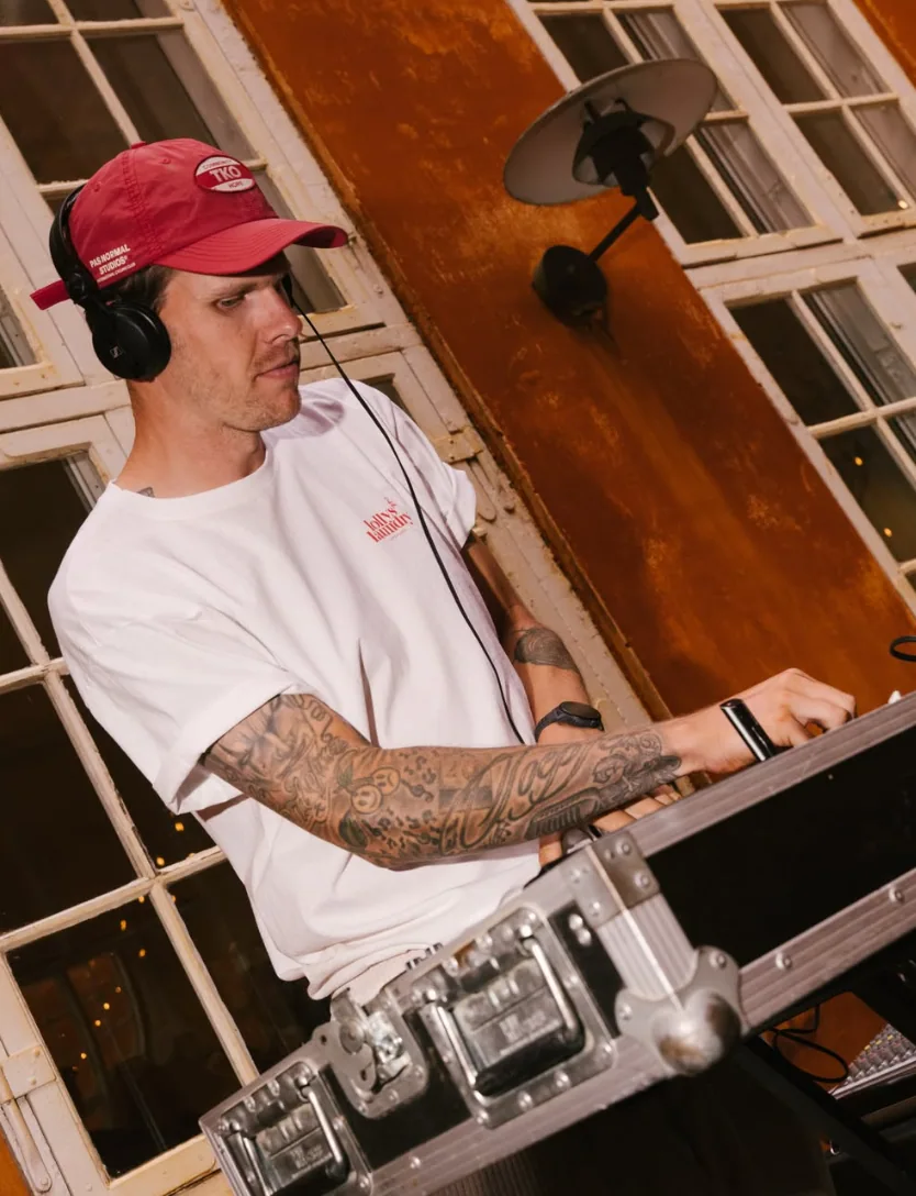 Mark Toepfer med rød cap og hovedtelefoner bag DJ-pulten